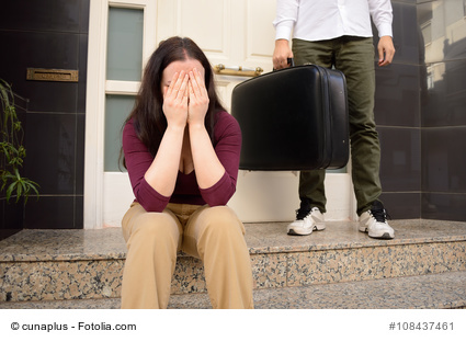 woman expelled of home sitting and weeping and the wife holding the suitcase of husband in background at the doorway as concept of divorce